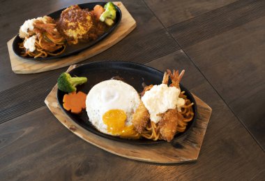 Ahşap bir masada kızarmış karides ve Japon tarzı biftek.