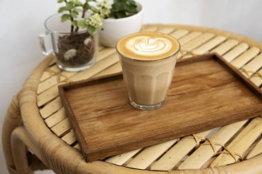 Hot latte in a wooden tray on a bamboo table clipart