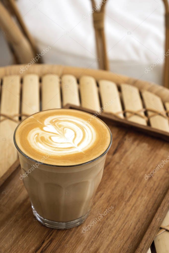 Hot latte in a wooden tray on a bamboo table