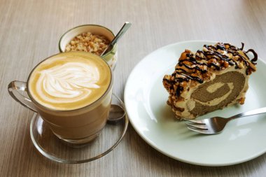 Ahşap bir masada sıcak latte ve rulo pasta
