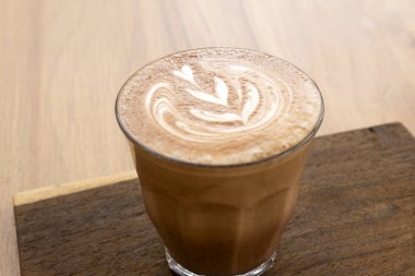 Ahşap zeminler üzerinde sıcak latte ve güzel sanat latte