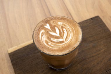 Ahşap zeminler üzerinde sıcak latte ve güzel sanat latte