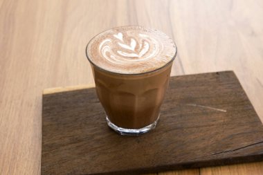 Ahşap zeminler üzerinde sıcak latte ve güzel sanat latte