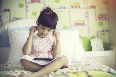 Asyalı çocuklar akıllı telefon ile müzik dinlemek için kulaklık kullanarak