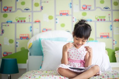 Asyalı çocuklar akıllı telefon ile müzik dinlemek için kulaklık kullanarak