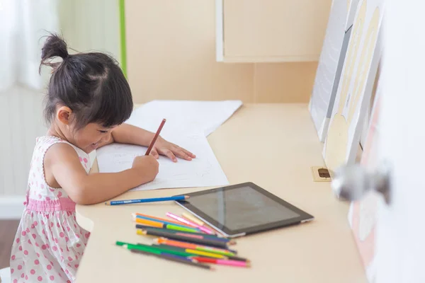 Pequena criança asiática usando um lápis para escrever no caderno no de — Fotografia de Stock