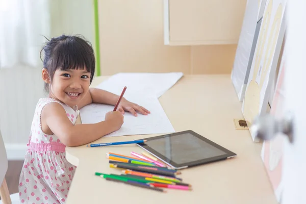 Pequena criança asiática usando um lápis para escrever no caderno no de — Fotografia de Stock