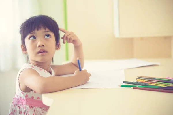 Little Asian dziecko za pomocą ołówka pisać na notebooku w de — Zdjęcie stockowe