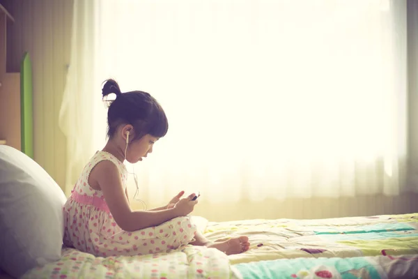 Азіатські діти використовують навушники для прослуховування музики на смартфоні — стокове фото
