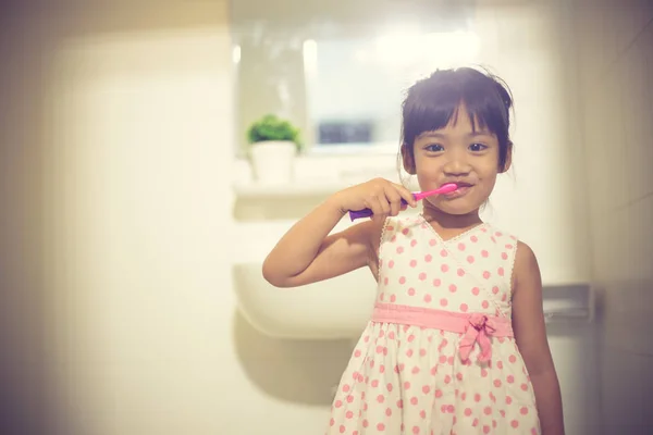 Маленька мила дівчинка очищає зуби щіткою в — стокове фото