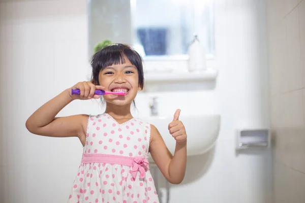 Маленька мила дівчинка очищає зуби щіткою в — стокове фото