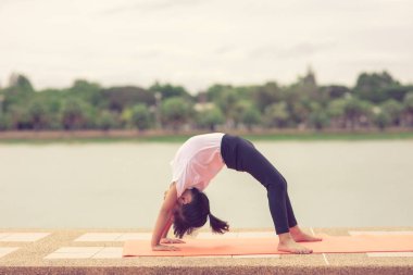 Küçük sevimli asya kız yoga yoga parkta bir paspas üzerinde poz, O