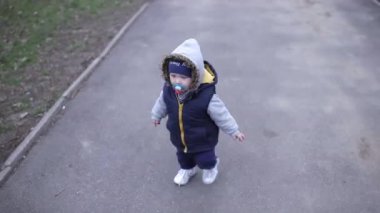 Ağzında emzik olan bebek asfaltta yürüyor