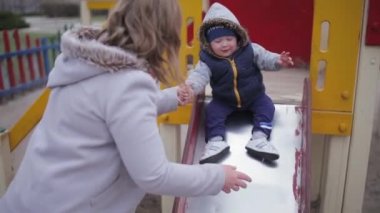 Çocuk tepeden aşağı inip annelerin ellerine doğru geliyor..