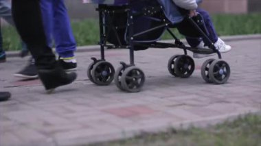 Kız kaldırım taşları üzerinde bir çocuk ile bir bebek arabası taşır