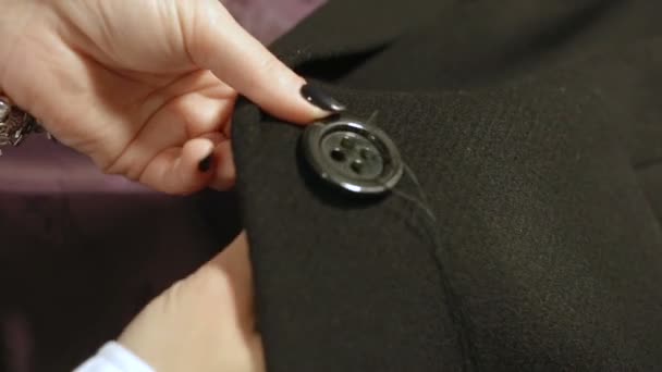 女人在黑色的黑色外套上缝上纽扣 — 图库视频影像