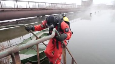 Kırmızı dalış ekipmanları profesyonel bir dalgıç, korkuluklar üzerine tutarak, suya dalış.