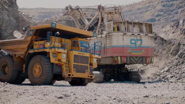一台采矿挖掘机将铁矿石装载到大型自卸卡车中 — 图库视频影像