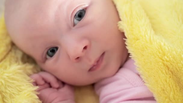 生まれたばかりの赤ん坊は黄色い毛布に包まれた変化するテーブルの上に横たわり 目をそらす — ストック動画