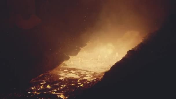 Un jet de métal fondu coule sous pression d'un haut fourneau. Vaporisateurs de métal volent autour .