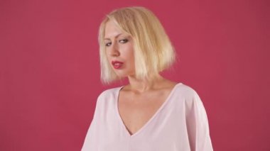 Pembe bluz beyaz kısa saçlı güzel genç kız. Stüdyodaki pembe bir arka plandaki kız. Moda, butik, reklam.