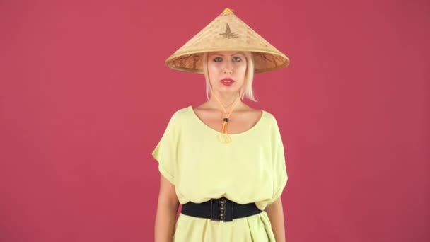 美丽的欧洲女孩与黑粉色的背景在稻草圆锥形帽子 并收紧帽子上的领带 — 图库视频影像