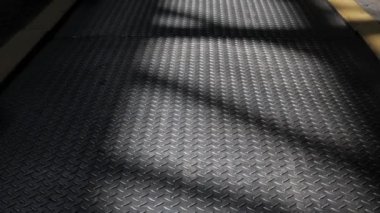 Kamera yükseliyor. Pencerelerin yansıtıldığı atölyenin metal tabanı.