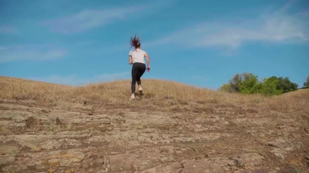 Een Sportieve Jonge Vrouw Rent Van Een Heuvel — Stockvideo
