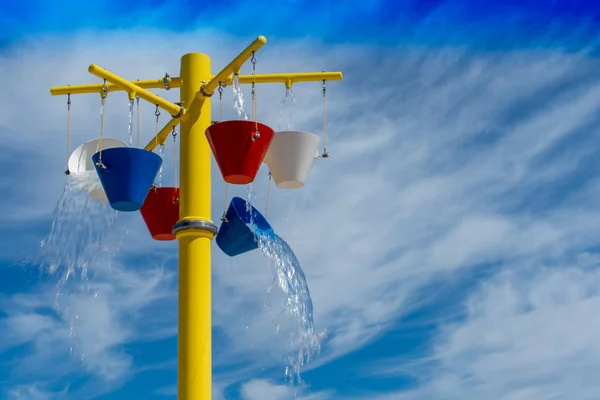 Colorful buckets of water pouring water on kids