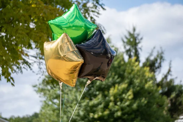 Gold black and green balloons outside a party