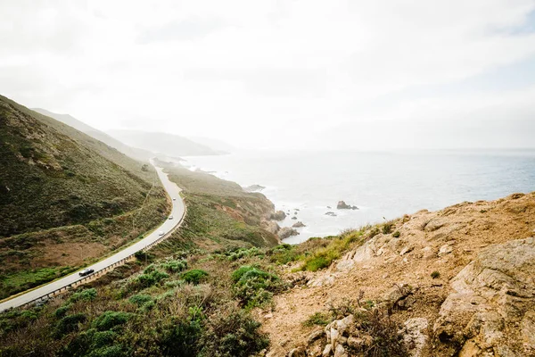 Caminho nas montanhas de uma estrada e escova verde que leva ao oceano — Fotografia de Stock