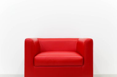 Mobilya kırmızı kanepe beyaz çimento duvar yanında yer almaktadır.