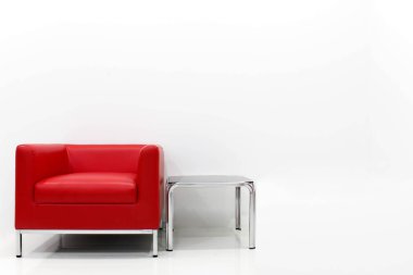 Mobilya seti kırmızı kanepe beyaz çimento duvar yanında yer almaktadır