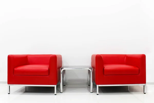 Furniture set red sofa is located next to the white cement wall.