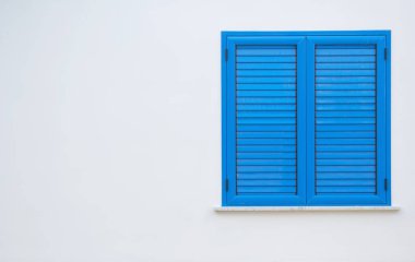 Avrupa 'da karantina, evde kal. Beyaz bir duvarda mavi panjurlu pencere. Kapalı panjurlu pencere. Evin duvarındaki mavi pencere..