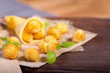 Peynir topları ahşap bir masa üzerinde fesleğen yaprakları ile. Peynir aperatifler bira için.