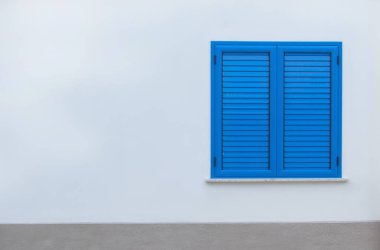 Avrupa 'da karantina, evde kal.. Beyaz bir duvarda mavi panjurlu pencere. Kapalı panjurlu pencere. Evin duvarındaki mavi pencere..