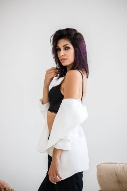 Siyah pantolon, beyaz ceket ve siyah sütyen evde çiçek buketi arka plan üzerinde ayakta giyen güzel esmer kadın portresi stüdyo 