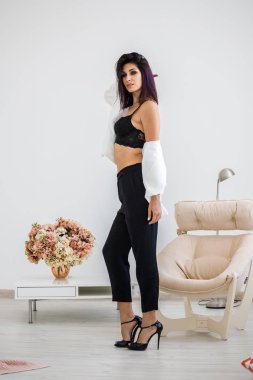 Siyah pantolon, beyaz ceket ve siyah sütyen evde çiçek buketi arka plan üzerinde ayakta giyen güzel esmer kadın portresi stüdyo 