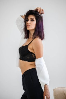 Siyah pantolon, beyaz ceket ve siyah sütyen evde çiçek buketi arka plan üzerinde ayakta giyen güzel esmer kadın portresi stüdyo 