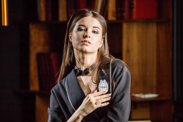 Kitaplık üzerinde arka plan ile ev iç pembe tişört ve siyah takım ayakta giyen güzel esmer kadın portresi 