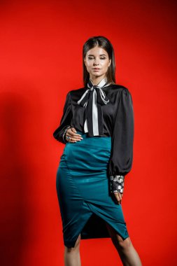 Genç model kırmızı bir arka plan üzerinde rahat kıyafetler içinde stüdyo portre. Siyah gömlek ve mavi etek stüdyoda poz genç kadın 