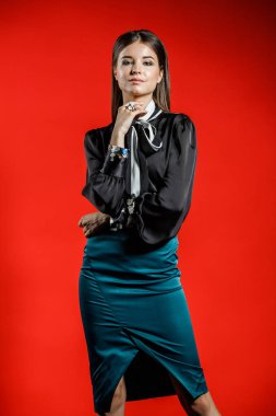 Genç model kırmızı bir arka plan üzerinde rahat kıyafetler içinde stüdyo portre. Siyah gömlek ve mavi etek stüdyoda poz genç kadın 