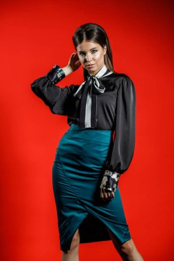 Genç model kırmızı bir arka plan üzerinde rahat kıyafetler içinde stüdyo portre. Siyah gömlek ve mavi etek stüdyoda poz genç kadın 