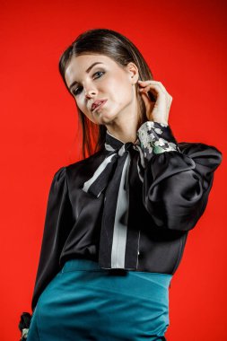 Genç model kırmızı bir arka plan üzerinde rahat kıyafetler içinde stüdyo portre. Siyah gömlek ve mavi etek stüdyoda poz genç kadın 