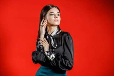 Genç model kırmızı bir arka plan üzerinde rahat kıyafetler içinde stüdyo portre. Siyah gömlek ve mavi etek stüdyoda poz genç kadın 