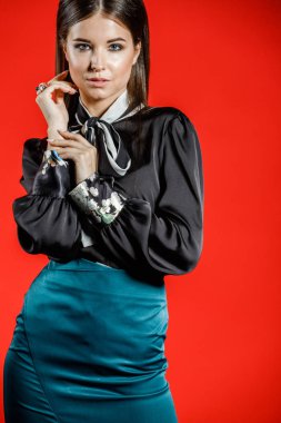 Genç model kırmızı bir arka plan üzerinde rahat kıyafetler içinde stüdyo portre. Siyah gömlek ve mavi etek stüdyoda poz genç kadın 