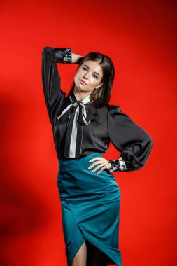 Genç model kırmızı bir arka plan üzerinde rahat kıyafetler içinde stüdyo portre. Siyah gömlek ve mavi etek stüdyoda poz genç kadın 