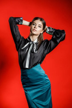 Genç model kırmızı bir arka plan üzerinde rahat kıyafetler içinde stüdyo portre. Siyah gömlek ve mavi etek stüdyoda poz genç kadın 