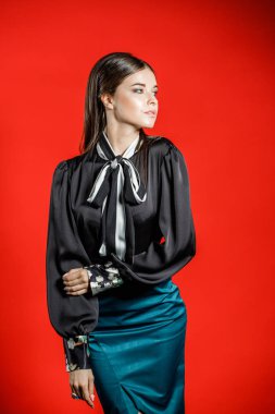 Genç model kırmızı bir arka plan üzerinde rahat kıyafetler içinde stüdyo portre. Siyah gömlek ve mavi etek stüdyoda poz genç kadın 